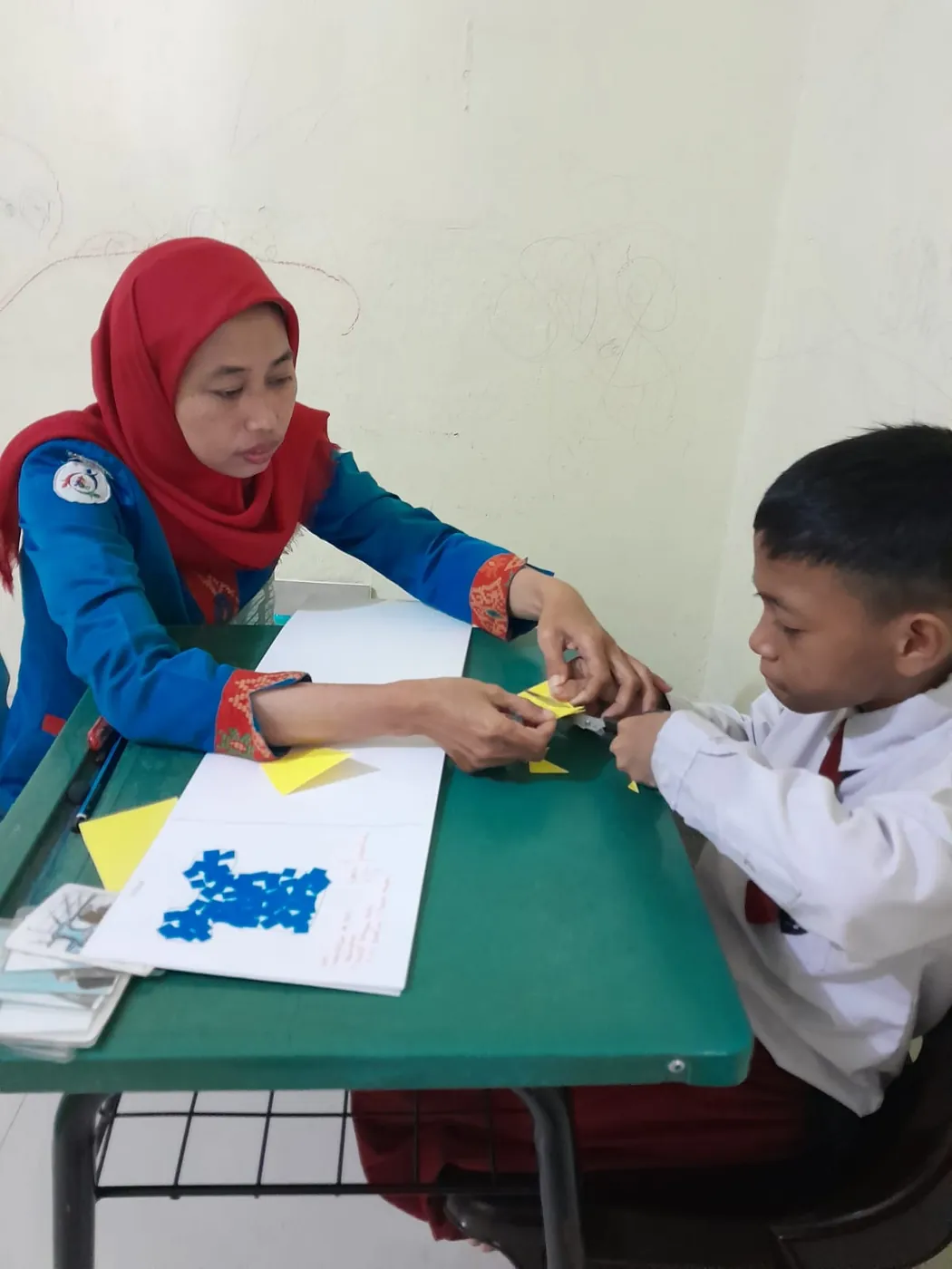 Guru SLB Putrakami mendampingi siswa membuat kerajinan dari kertas